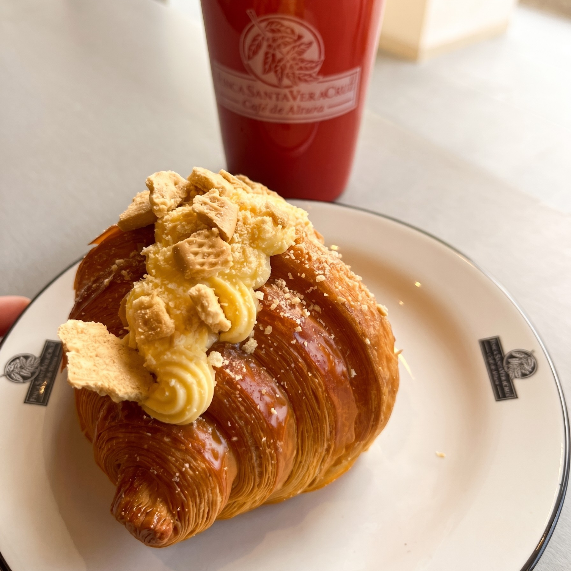 Croissant con crema y galleta con taza roja